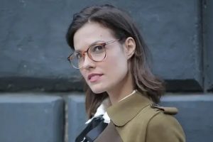 Woman wearing stylish eyeglasses posing in front of a dark background