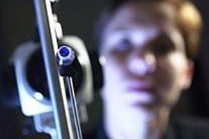 Close-up of a slit-lamp eye exam tool with a blurred background of a patient during an eye test